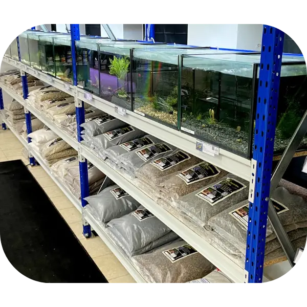 Ladenregal mit Aquarien in Schaukästen und verschiedenen Aquarienkies-Sorten in Papiersäcken auf blauem Metallregal